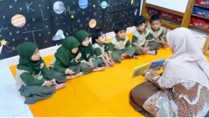 Anak mendengar guru membaca buku cerita